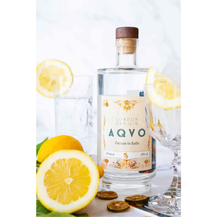 Bottiglia di AQVO London Dry Gin con limoni freschi e bicchiere, un gin artigianale italiano dal profilo aromatico agrumato e floreale