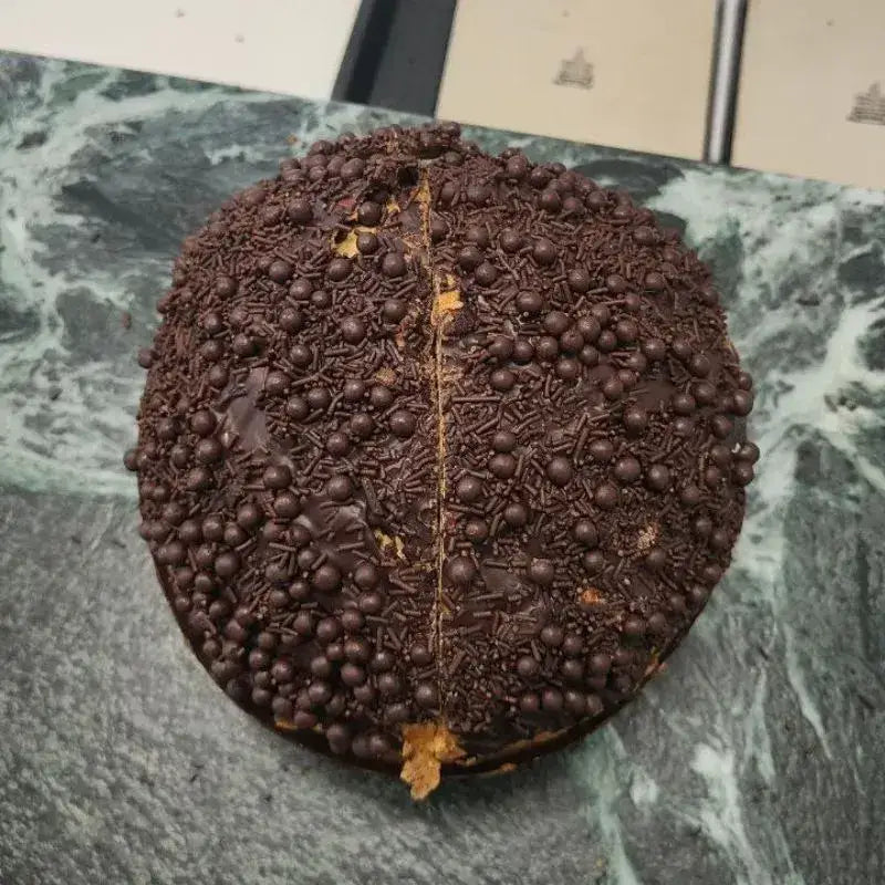 Vista dall’alto del panettone al cioccolato con ricca copertura di perle e granella di cioccolato.